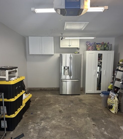 Garage with white wall cabinets installed above a refrigerator and storage
