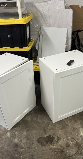 White wall cabinets staged on a garage floor before install