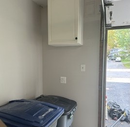 White wall cabinet mounted high beside a garage door