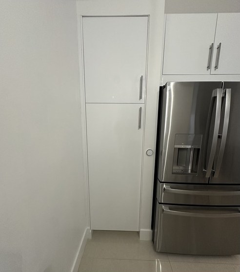 White high-gloss IKEA SEKTION tall pantry cabinet beside a refrigerator